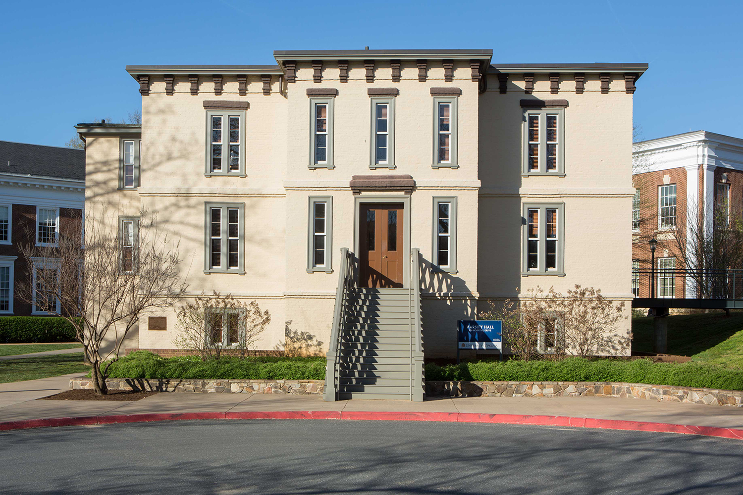 A modern image of a tan building with stairs approaching the front door.