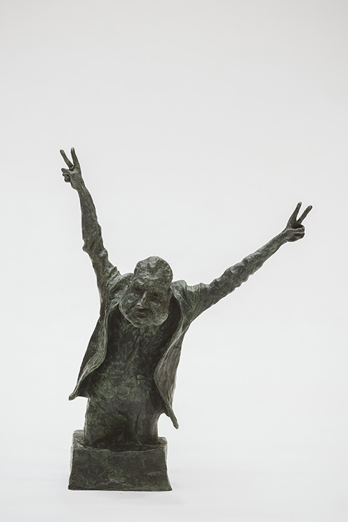 Nixon as a three-quarter figure, his shoulders hunched as he raises his arms to make his characteristic double V for victory salute