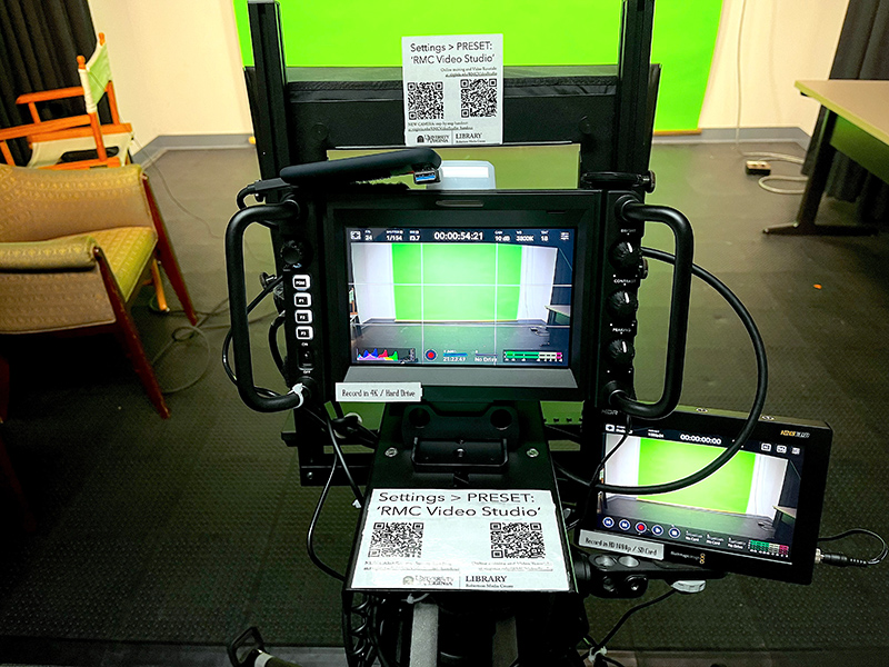 Close up of camera setup, with green screen and printed instructions visible