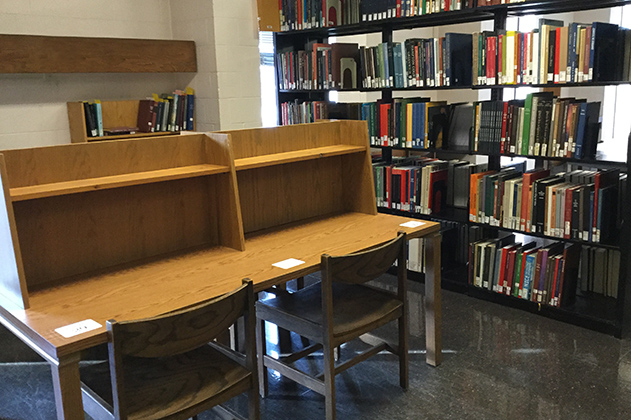 Two wooden desks are side by side among book shelves