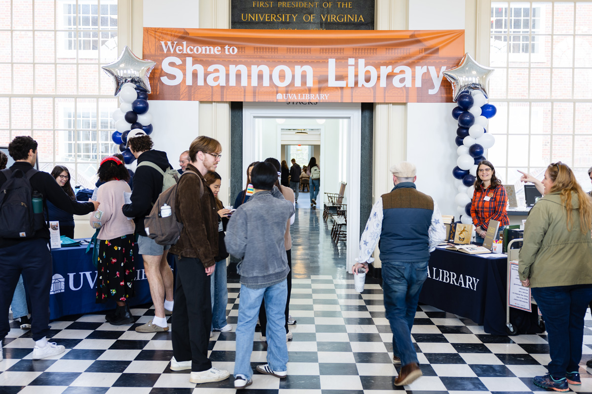 Students and visitors gather at a welcome event inside the University of Virginia's Shannon Library, where banners, balloons, and information tables are set up.