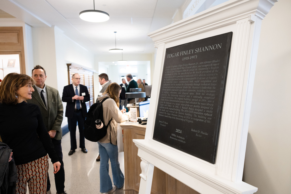 People gathered around a plaque dedicated to Edgar Finley Shannon at an event, reading and discussing the displayed information.