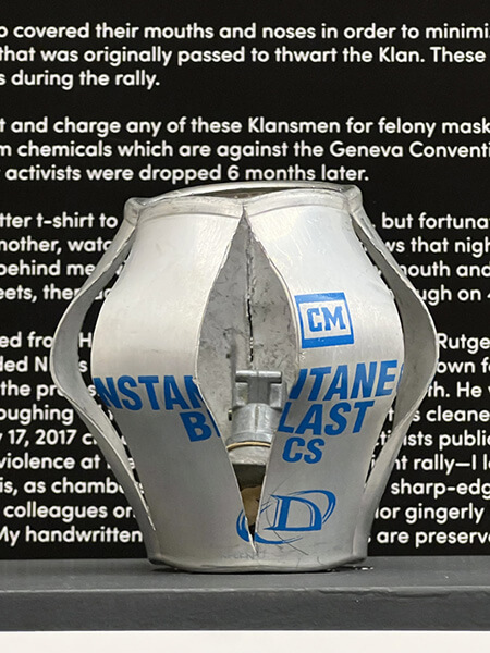 A metal canister is blasted open on the sides, showing metal pieces inside. The words Instantaneous Blast are visible on the outside of the canister.