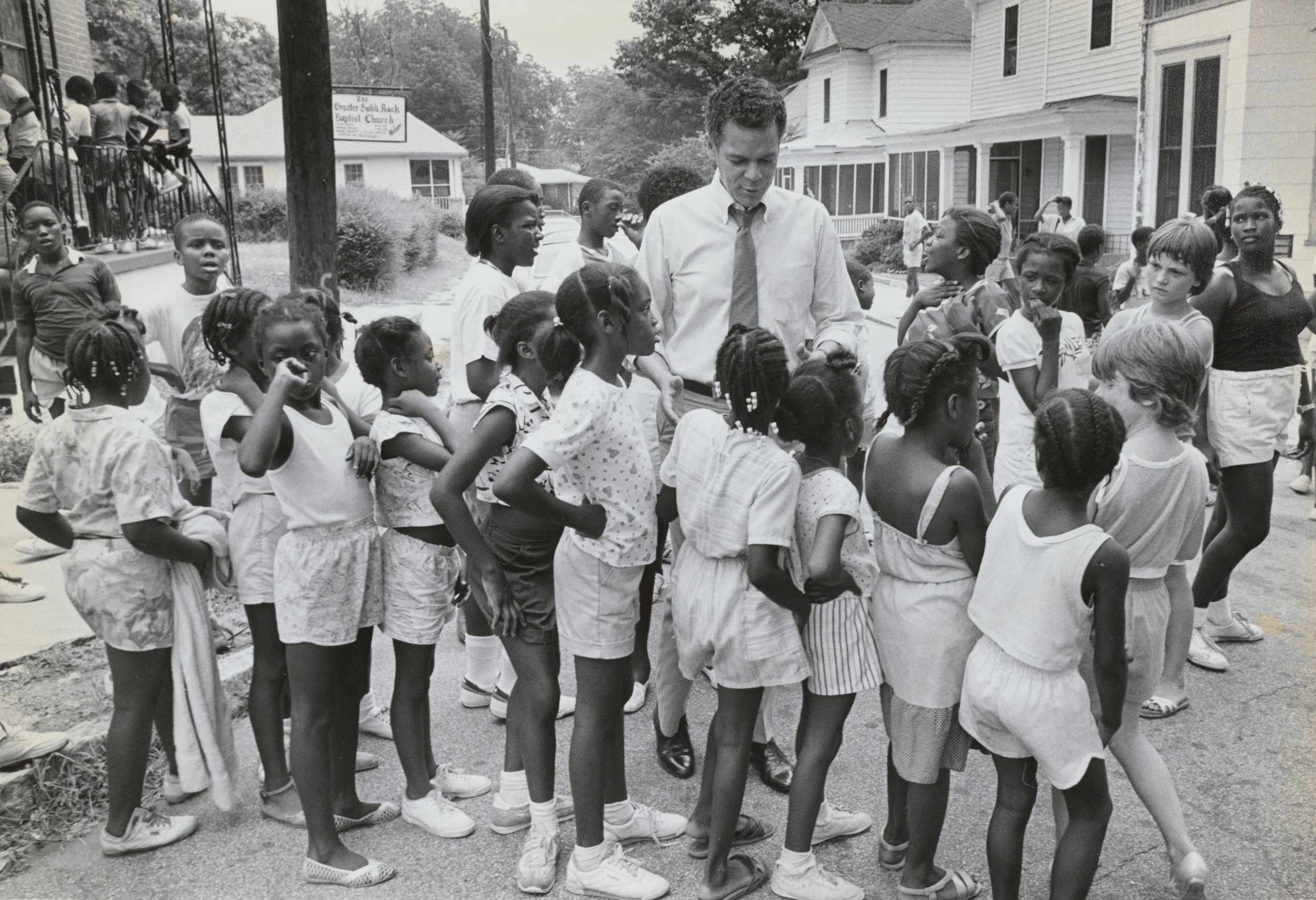 Julian Bond surrounded by a group of children in the American South.