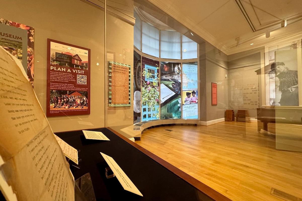 Interior of a museum exhibit featuring informational panels and displays visible through glass partitions, with textual and pictorial elements related to historical events.