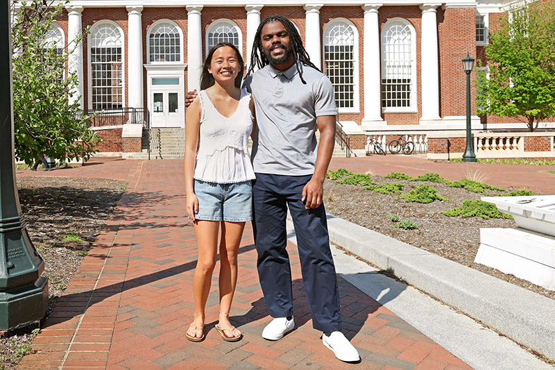 Two people standing and smiling in front of the University of Virginia's Shannon Library.