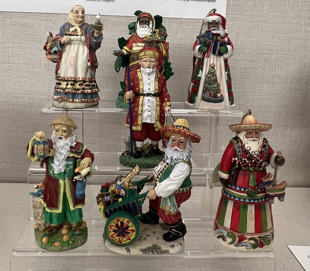 Seven figurines of Santa Claus of varying ethnicities and garments.