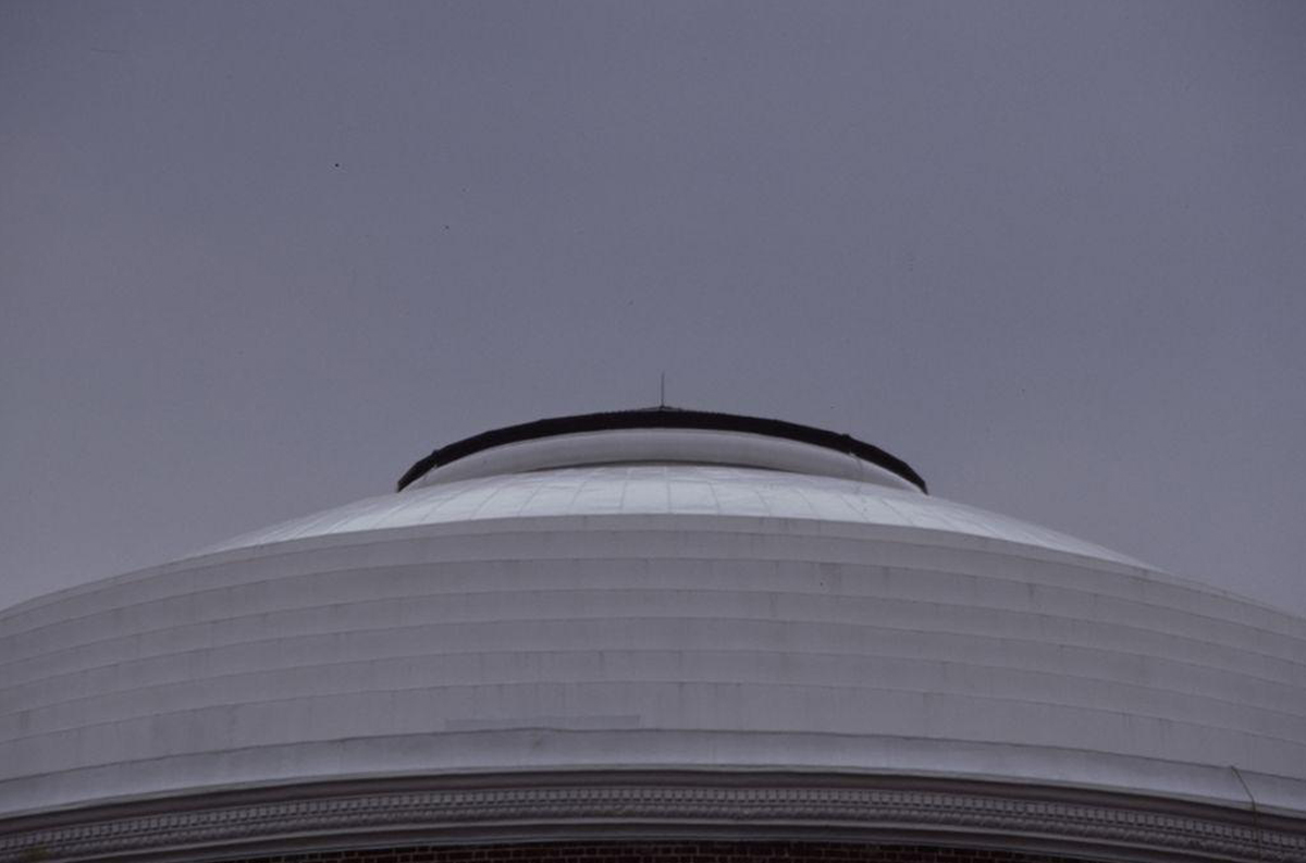 Detail of the circular dome of the UVA Rotunda featuring a layered, white exterior against a cloudy sky.