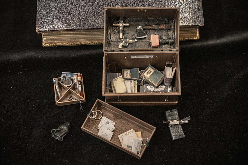 A miniature vampire hunting kit stocked with silver stakes, a vial of holy water, a cross, a mirror, and garlic.