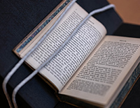A book lays open with weighed ropes to keep pages open