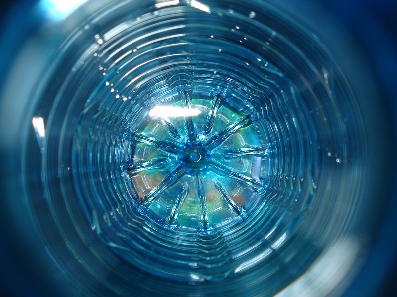 Close-up view looking down into a transparent, ribbed glass with circular patterns and a blue tint.